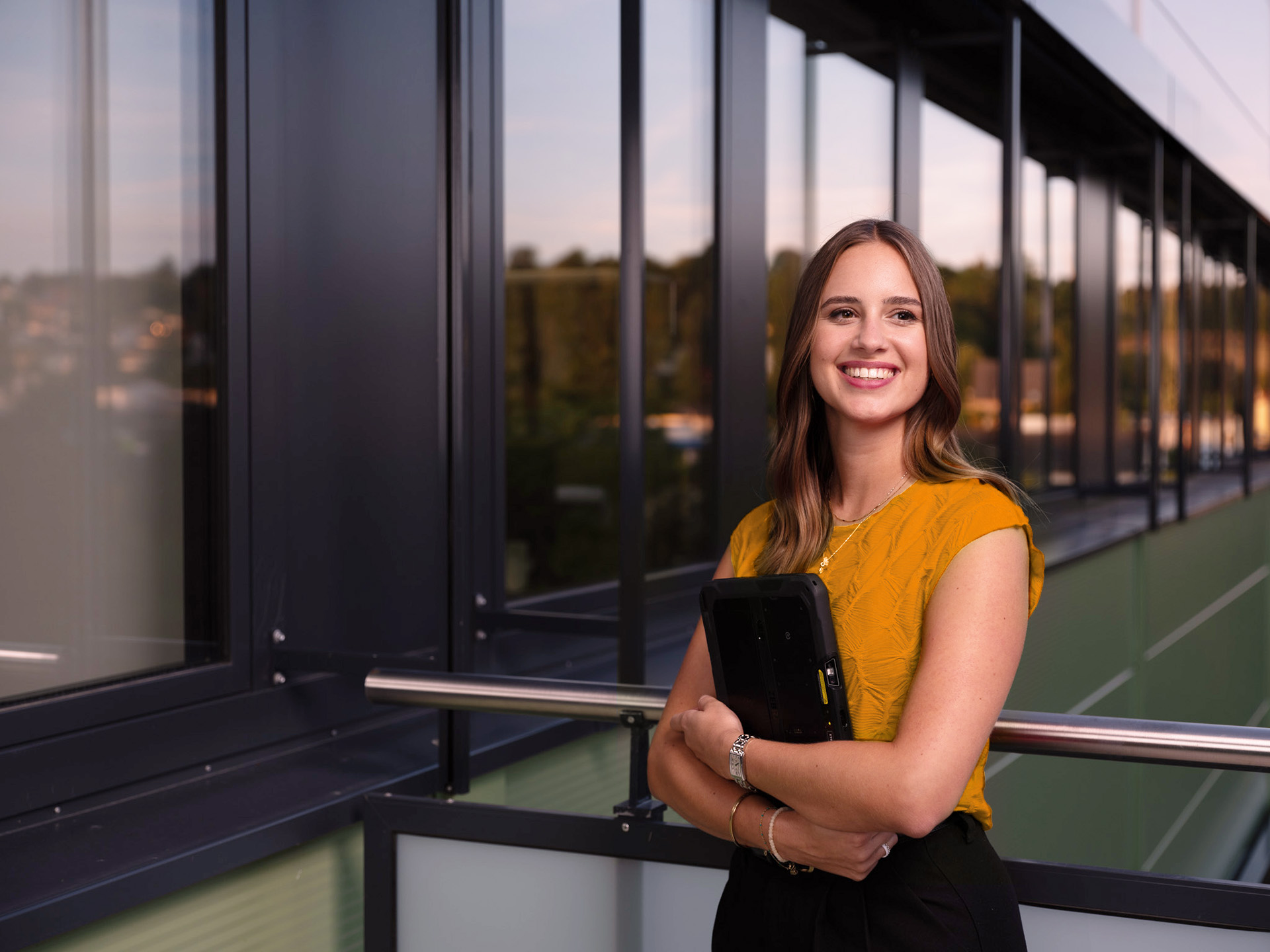 Milena Greim von Greim Consulting steht in einem modernen Bürogebäude und hält ein Tablet, symbolisierend die Unternehmensleistung in Prozessoptimierung, Supply Chain und E-Commerce-nahe Abläufen.