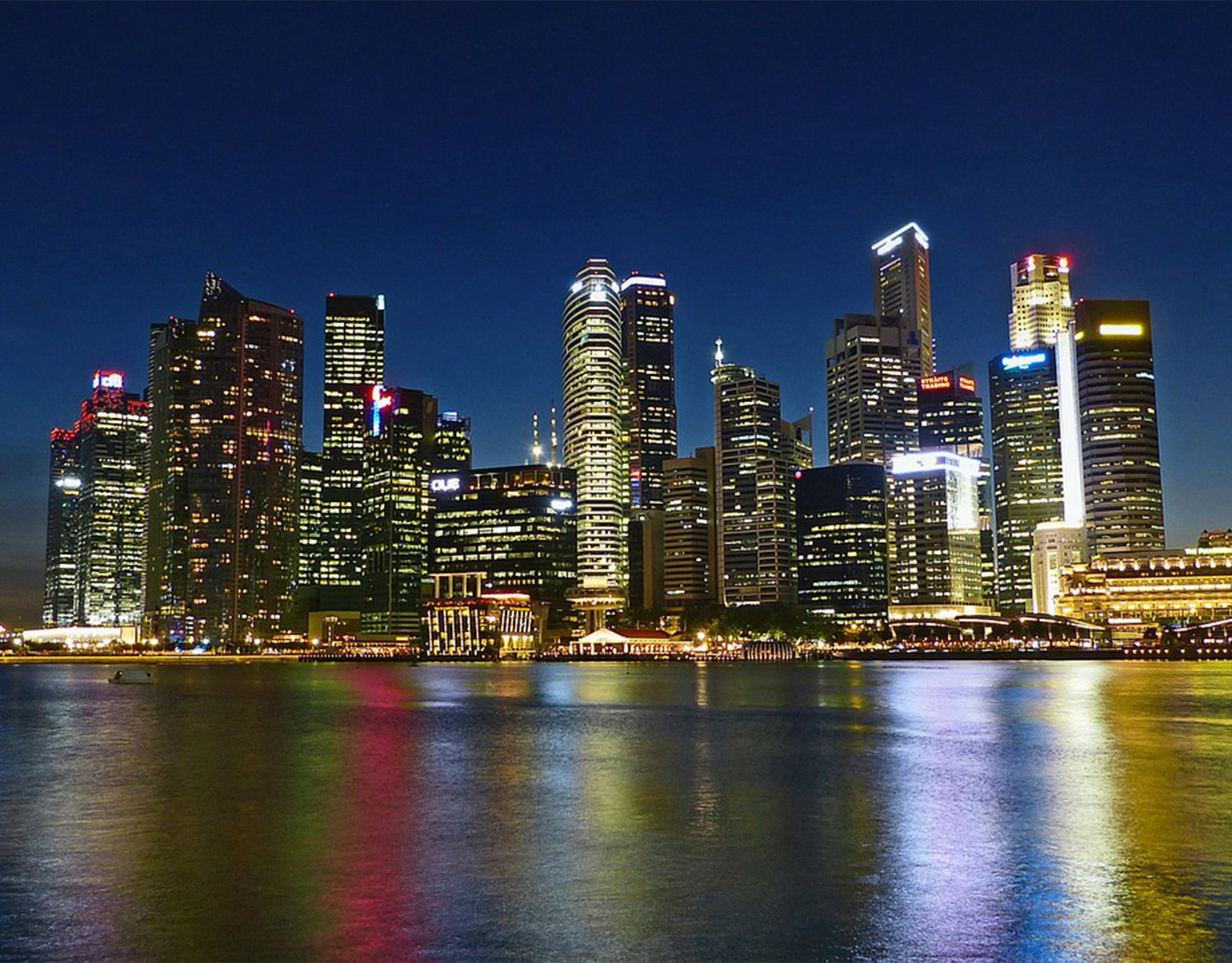Nachtliche Skyline einer modernen Metropole mit leuchtenden Hochhäusern und Wasserreflexionen – ein Bild von urbanem Wachstum und Effizienz, passend zum Fokus von Greim Consulting auf Prozessoptimierung und Supply Chain.